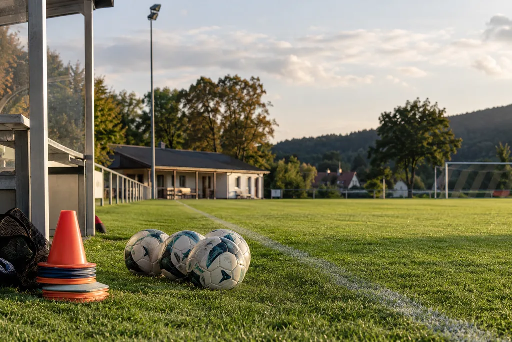 Sports field with footballs and training caps on the side of the pitch.